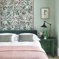 Bedroom with green walls and a botanical mural, with pink and green accents on the bedding