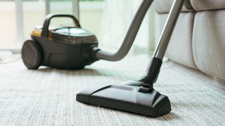 vacuum cleaning on carpeted floor to show how often you should clean your house