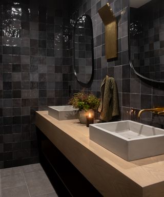 gray small bathroom ideas, dark gray bathroom tiles with wood floating vanity unit, double basins, pair of black mirrors, grey floor tiles
