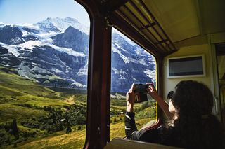 Woman taking photo with smartphone of scenery while riding in train