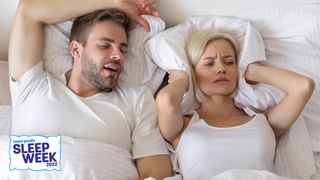 Women covers her ears with pillow next to snoring man