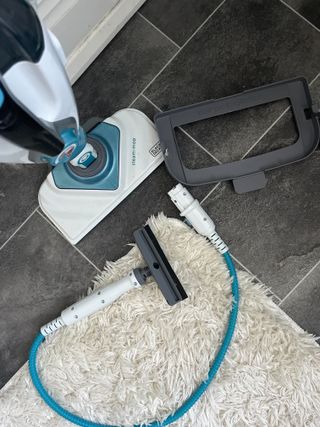 The bottom of a black and decker steam mop with the upholstery attachment and carpet glide attachment