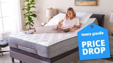 A woman relaxing on a GhostBed mattress in a GhostBed Adjustable Base, sitting in an inclined position. A Tom's Guide Price Drop deal's graphic (right)