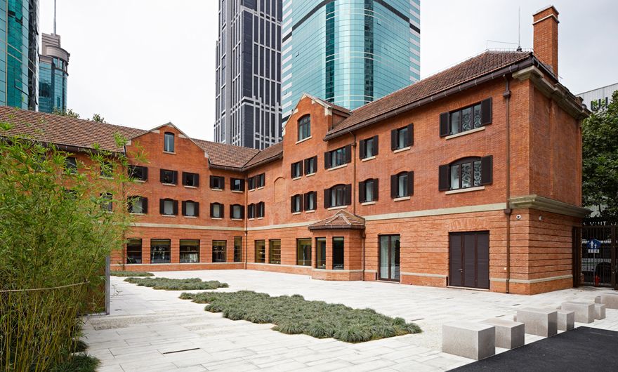 Red brick building with tiled roof and brown doors and windows with shutters