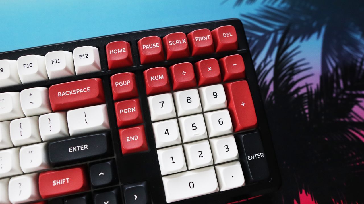 The Gamakay TK101 gaming keyboard in a red and white colourway and on a colourful mouse pad.
