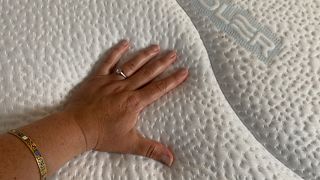 A hand rests on the surface of the Sleepeezee Cool Rest 1800 mattress, showing temperature regulation