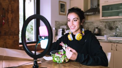 Woman eating a salad while on a video call with the best ring light pointed at her