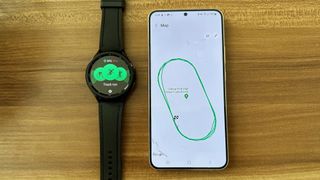 The Track Run sport mode on the Samsung Galaxy Watch 6, next to a Galaxy S22+ showing the results of a tracked workout. The GPS data shows the runner straying across the entire track, when it should show them staying in Lane 1.