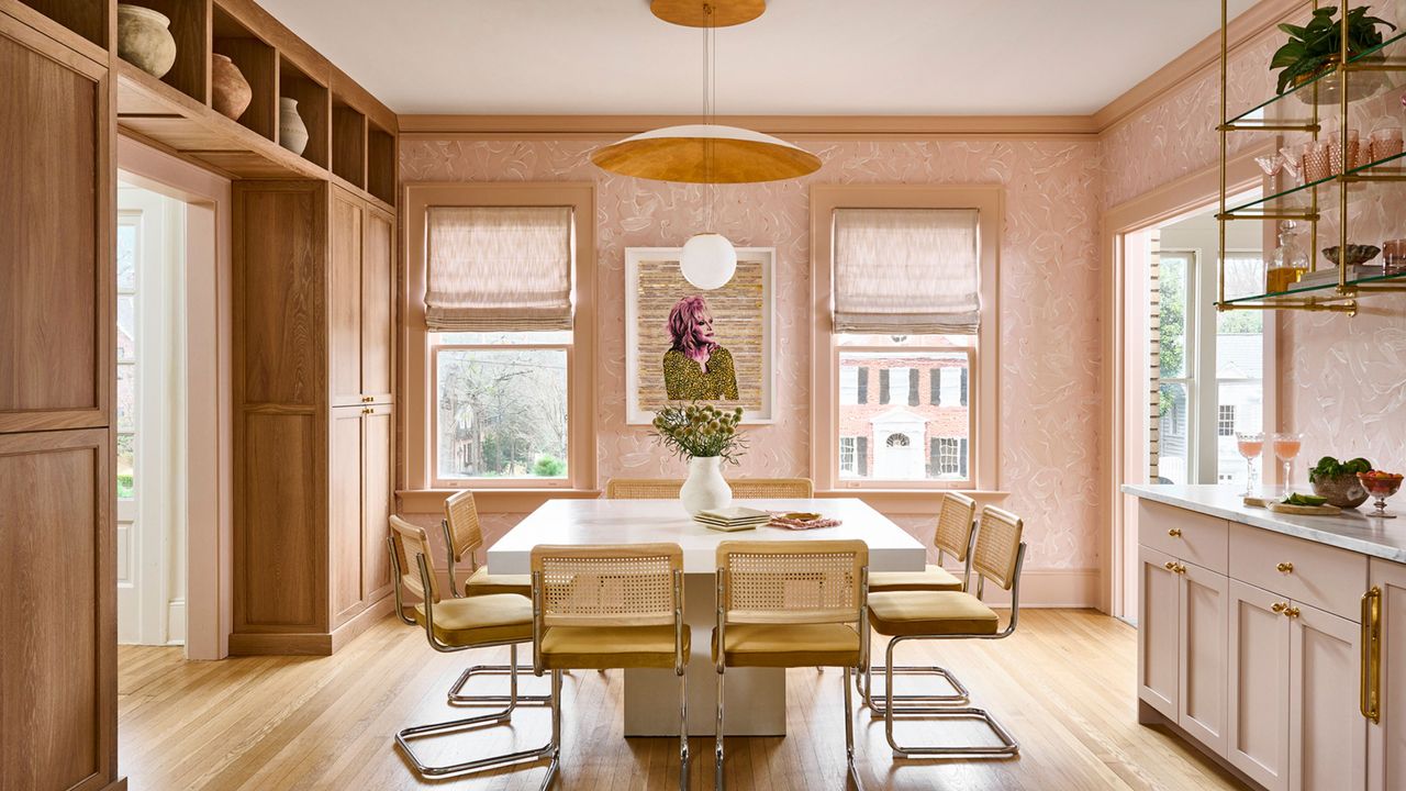 Cheerful dining room area with large, sun-filled windows, sandy wooden details, and sculptural lighting overhead