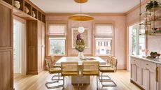Cheerful dining room area with large, sun-filled windows, sandy wooden details, and sculptural lighting overhead