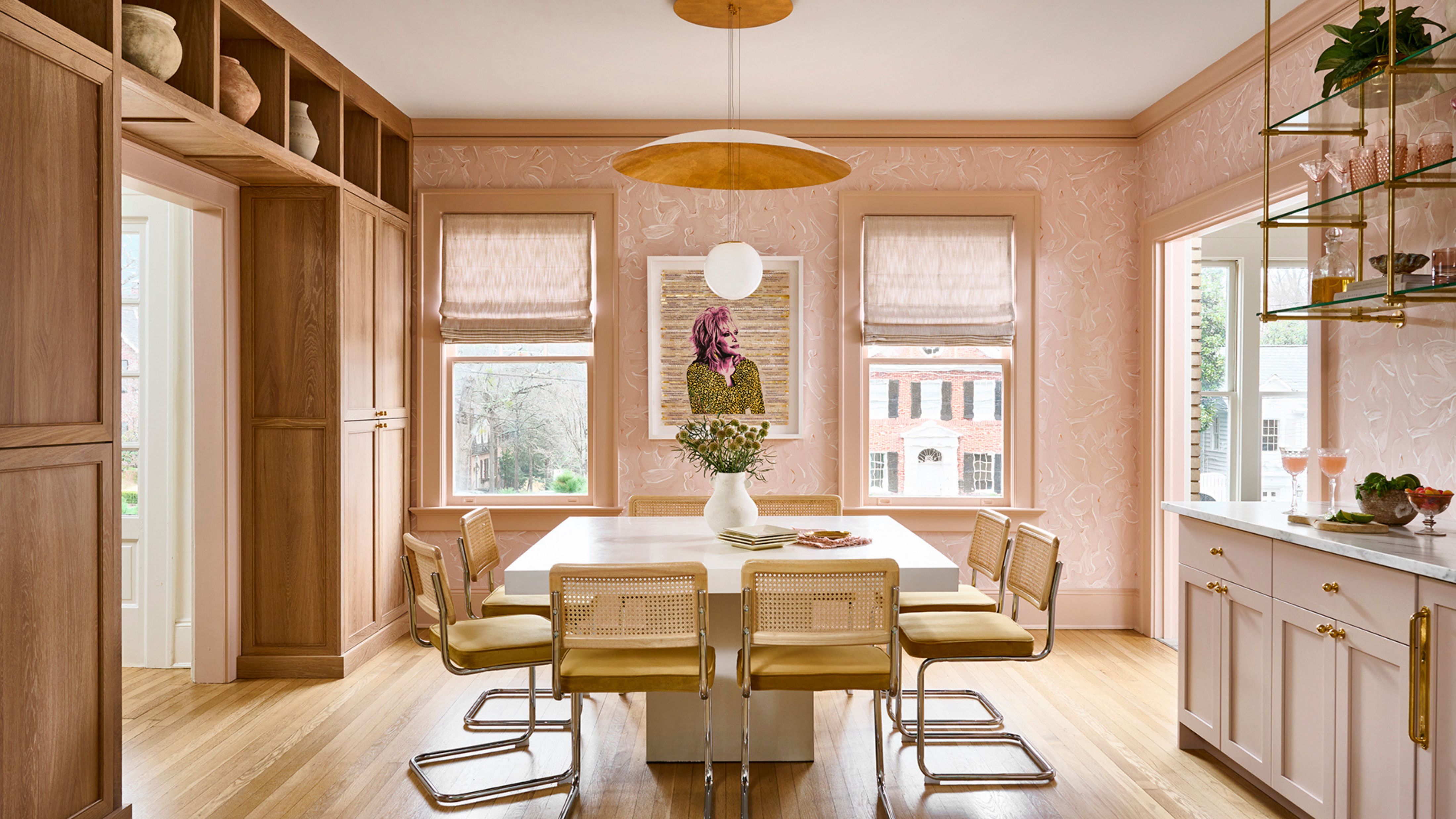 Cheerful dining room area with large, sun-filled windows, sandy wooden details, and sculptural lighting overhead