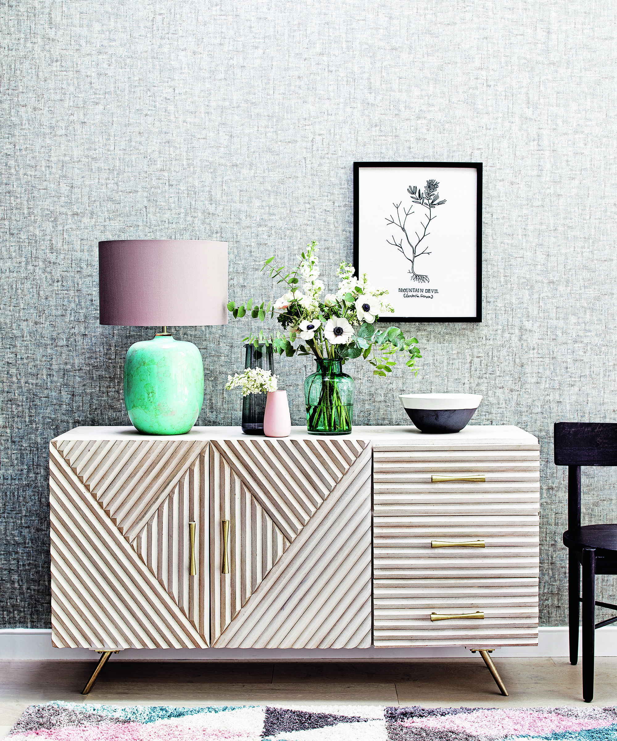 Grey living room ideas featuring a wooden sideboard with green lamp and grey textural wallpaper.
