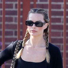 Margot Robbie wearing a black cardigan with leggings, ballet flats, and a Chanel bag in West Hollywood