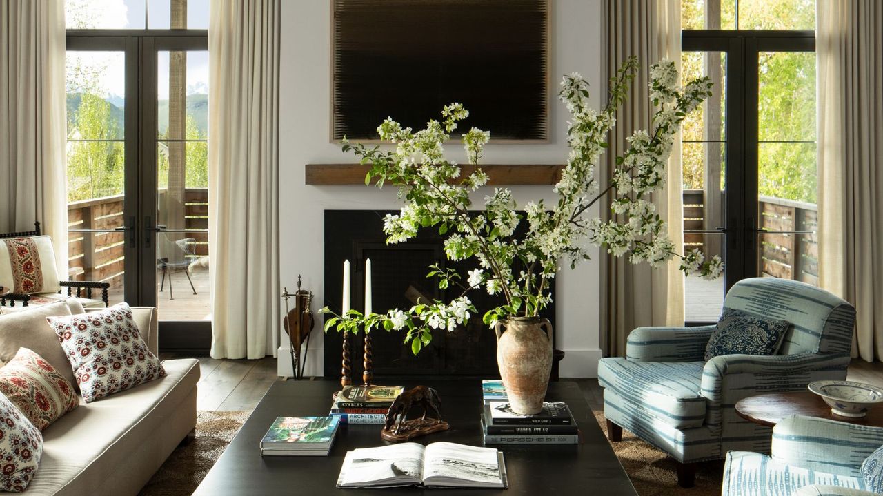 Farmhouse style living room with beams, large rustic floral arrangement, blue upholstered armchairs and coffee table