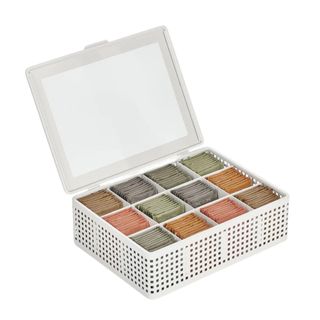 A white metal tea bag packet holder with brown, dark blue, sage green, peach, and orange packets in it