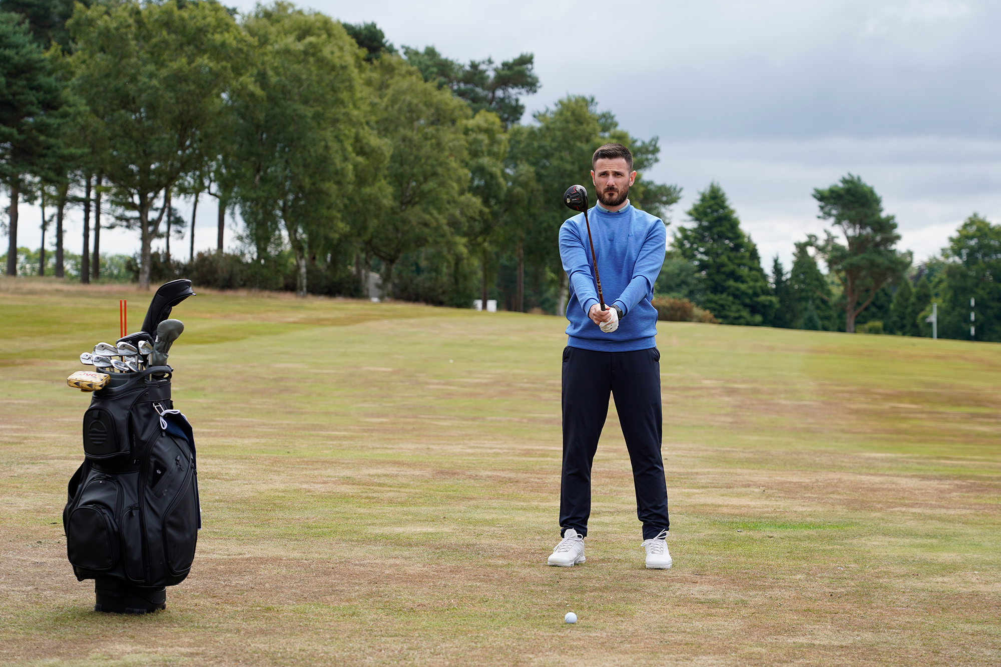 Barry Plummer preparing to hit a shot from the 1st fairway at Sand Moor Golf Club, holding a wood out in front of his body to visualise the shot he is about to play