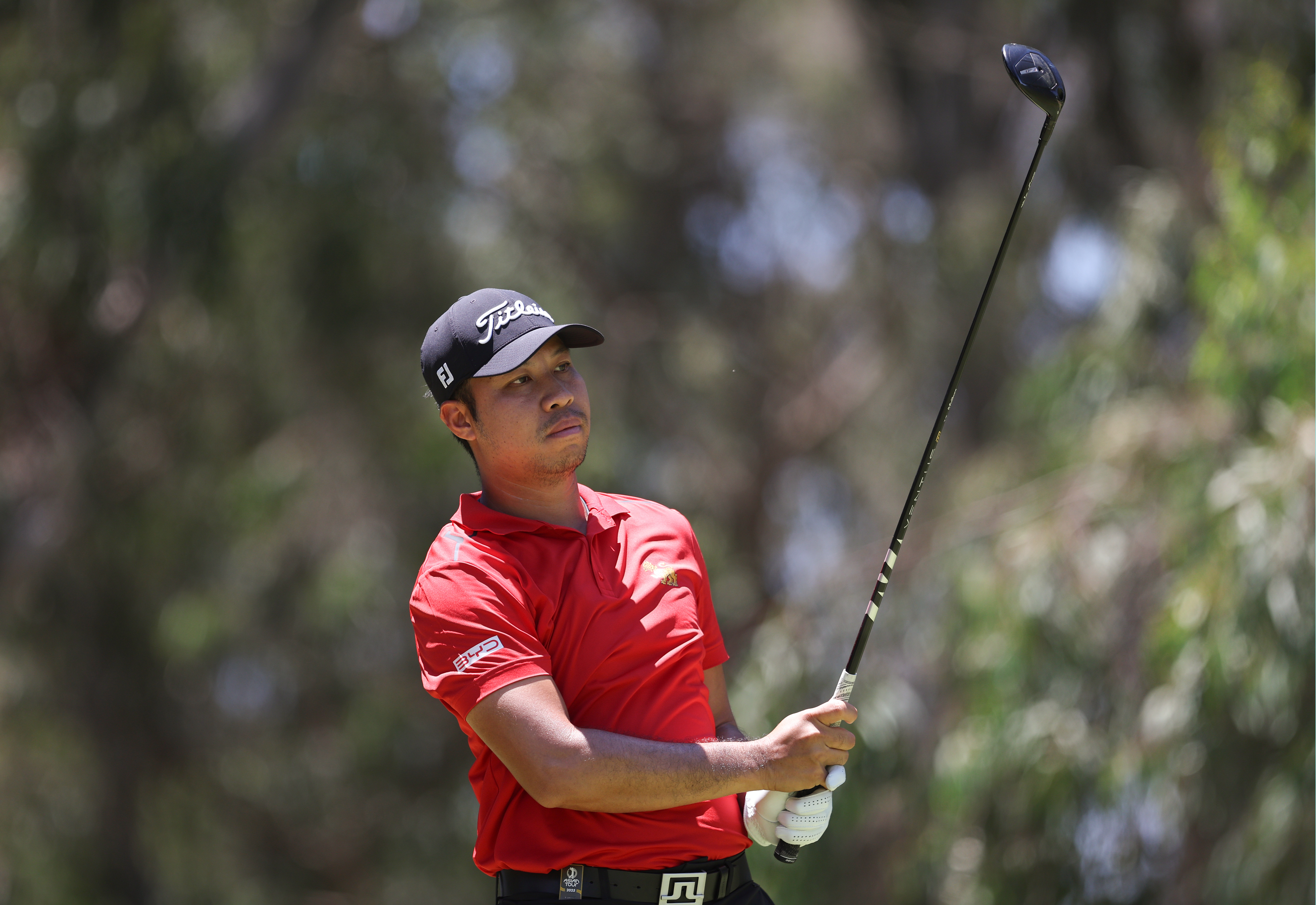 Danthai Boonma wearing a red polo and black Titleist cap holding his finish on a fairway wood shot