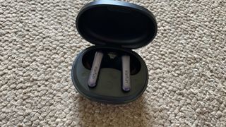 Earfun Air S earbuds and case on beige carpet