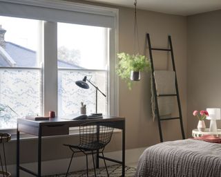 bedroom with large windows covered with film, a desk and storage ladder