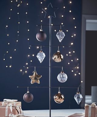 A black metal silhouette tree with metallic colored Christmas bauble decor