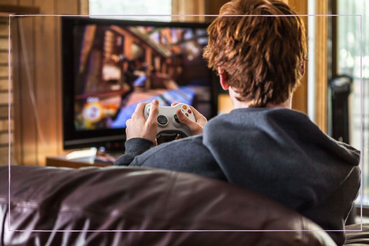 A teenage boy playing a video game pictured from behind