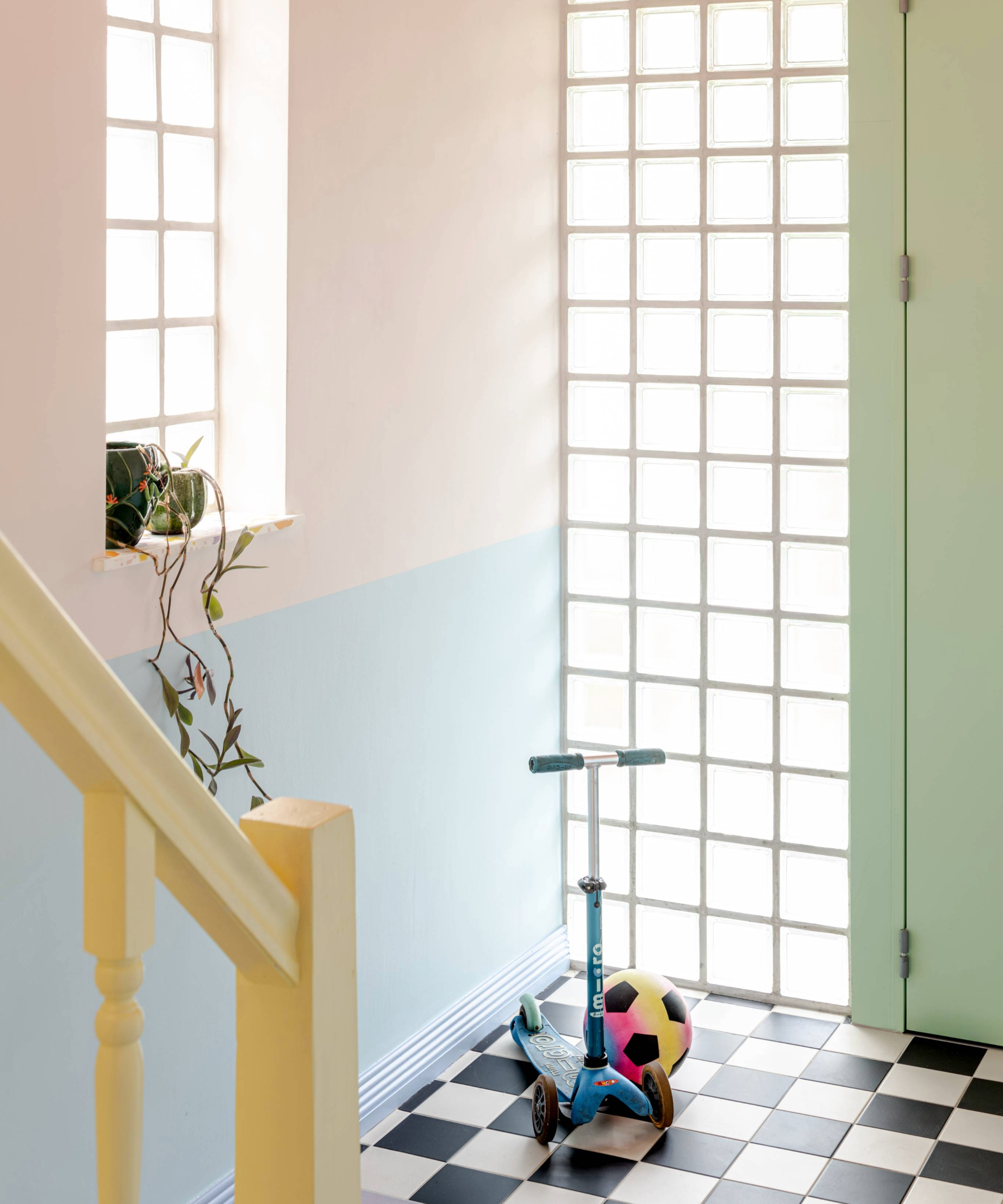 Front door entrance with chequered flooring, blue and pink walls and green front door 