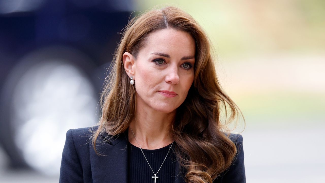 Kate Middleton wears a black blazer and black top and has wavy hair