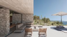 A minimalist backyard with sectional sofa seating and rattan chairs around a fireplace and a parasol over a sun lounger