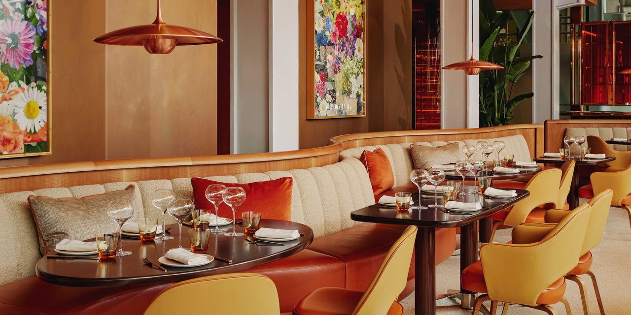 A modern glamorous restaurant with leather and wood furniture, copper lighting, and flowery wall art.