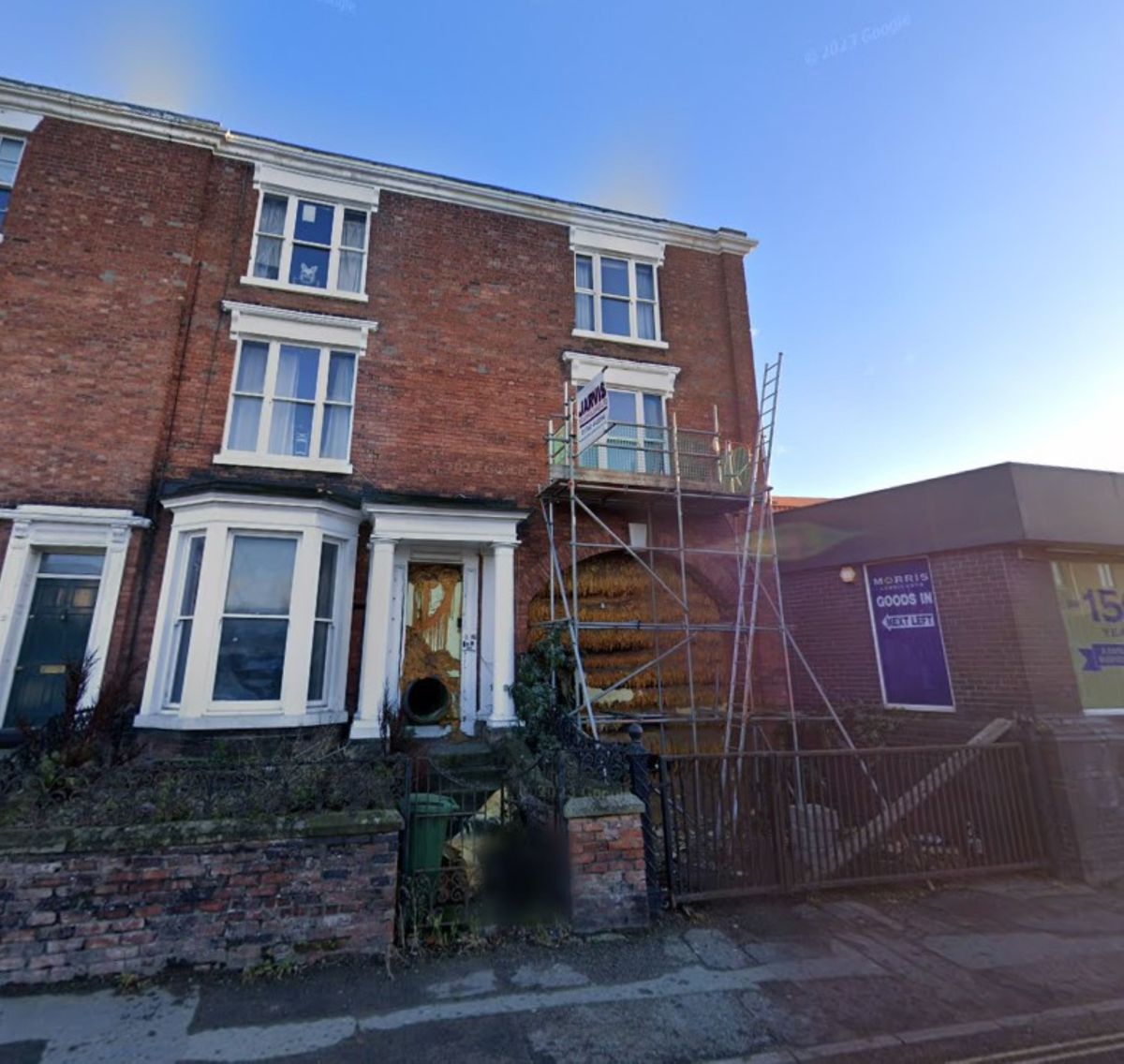 A house with an archway which is filled with pipes and foam and surrounding by scaffolding