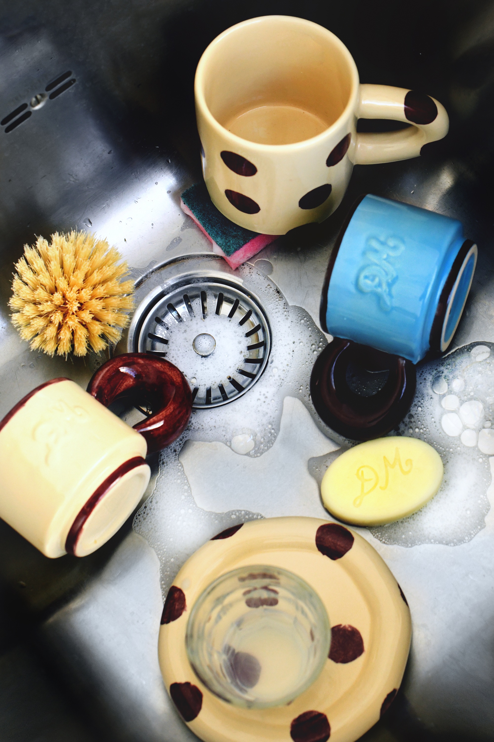 quirky plates and mugs in a sink