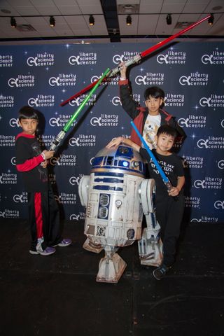 Visitors pose with R2-D2 Feb.12 at Liberty Science Center's "Science, Sabers & Star Wars" event. 
