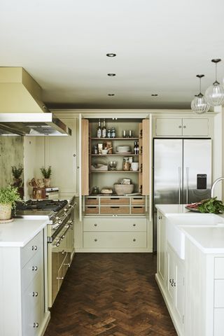 Beautiful modern cream kitchen ideas with hints of green, a butler sink and herringbone wood flooring.