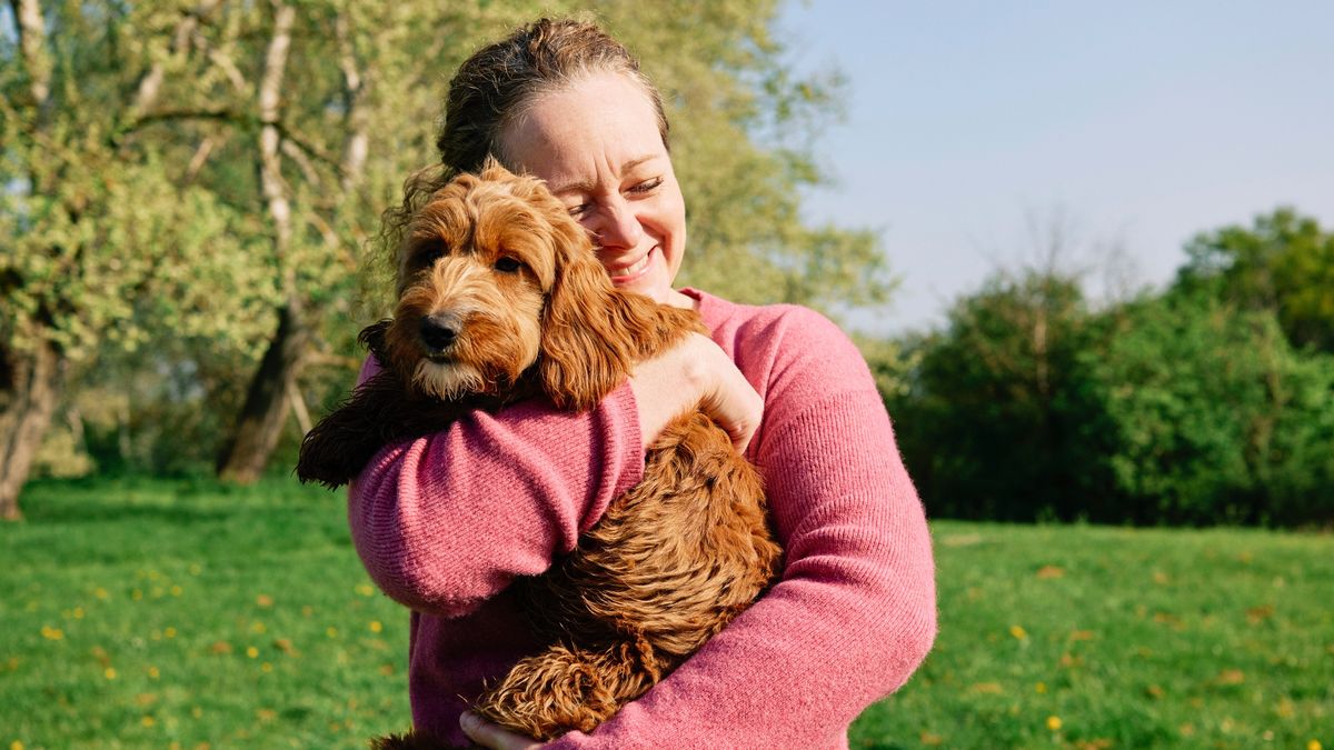 Woman cuddling her dog in a field