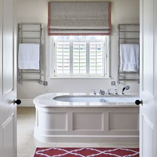 white bathroom with bathtub and red mat