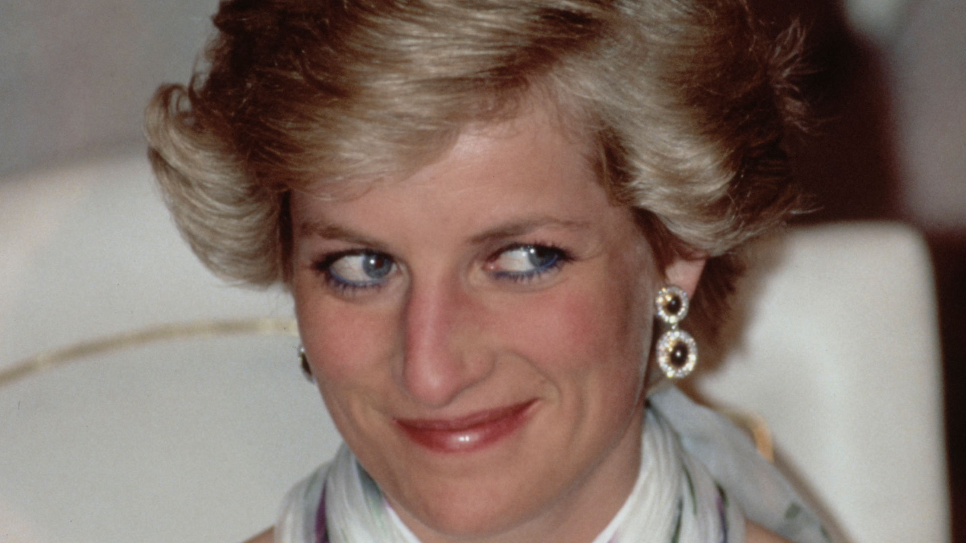 Princess Diana smirking and wearing diamond earrings