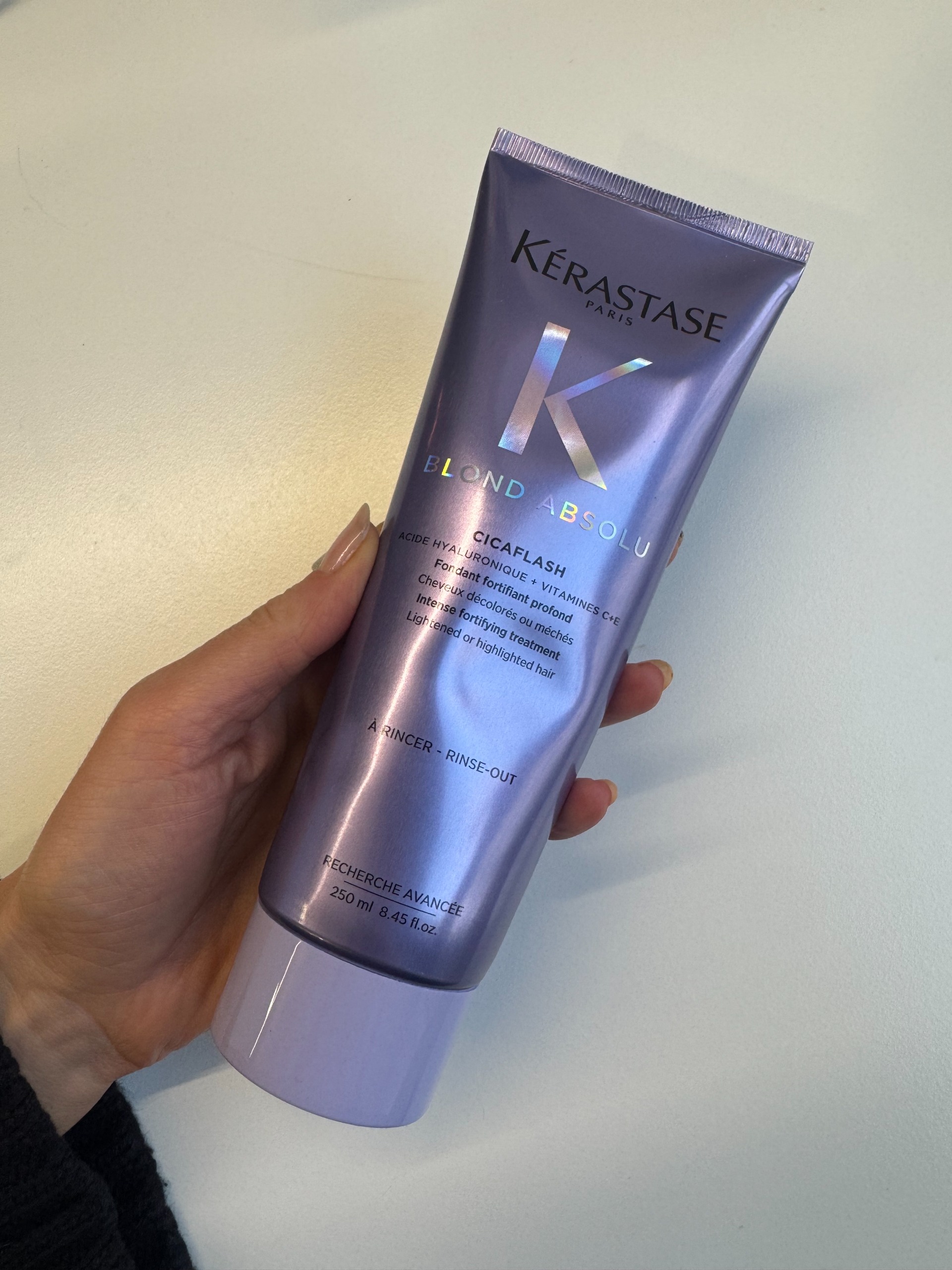 Eleanor holding a bottle of Kerastase blond absolu conditioner