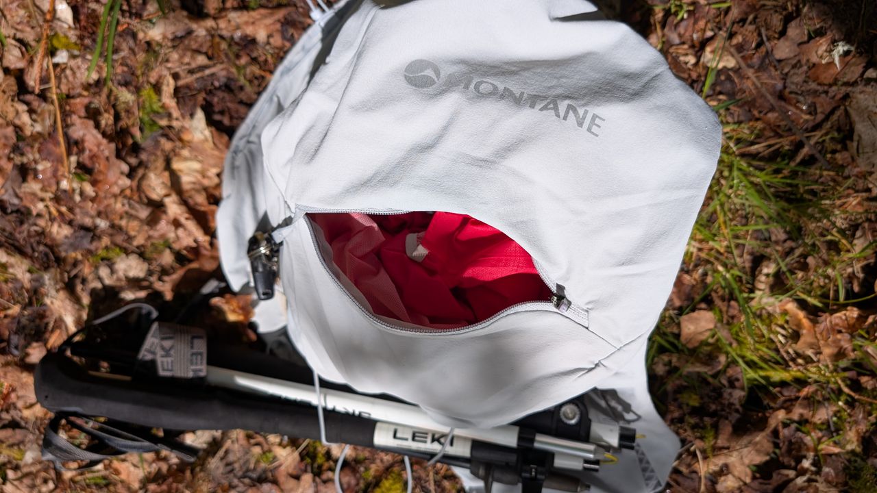 A grey Montane Gecko hydration vest on the ground, unzipped and showing gear inside