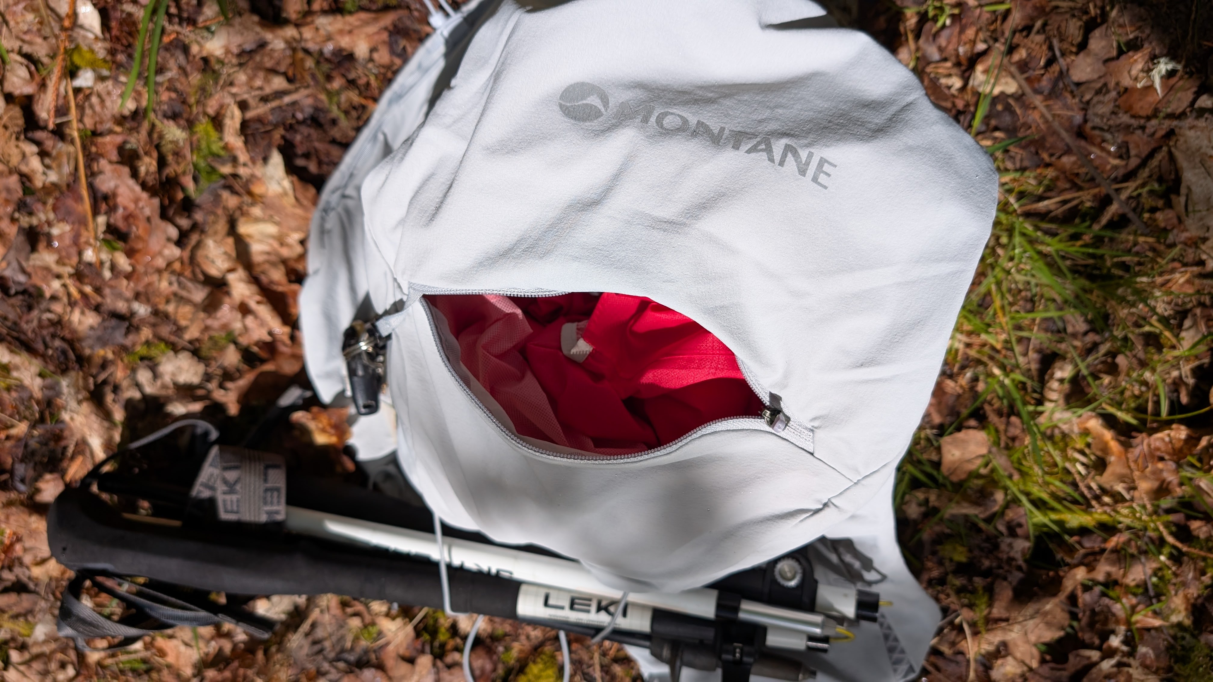 A grey Montane Gecko hydration vest on the ground, unzipped and showing gear inside