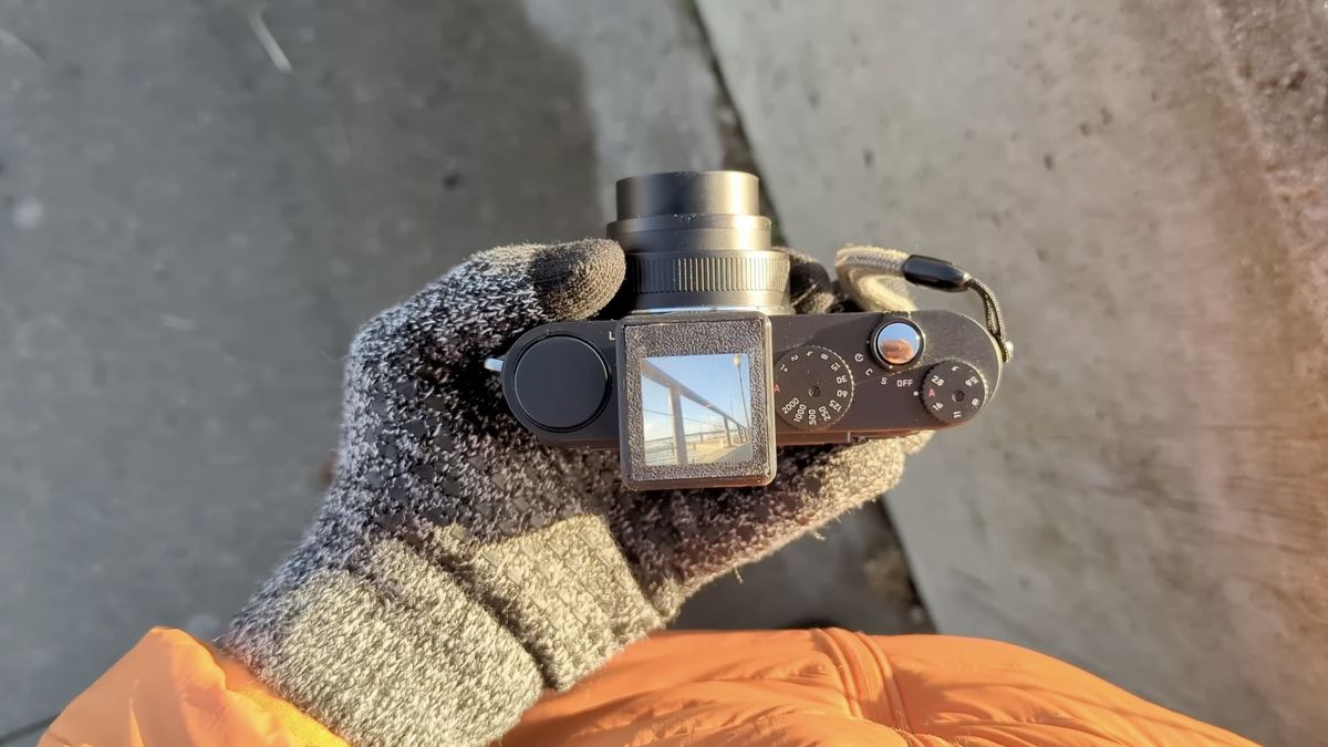 Top-down view of DIY waist-level viewfinder on a compact camera, being held in a gloved hand