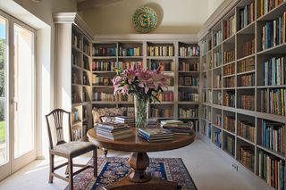 library with fitted bookshelves and round table with french doors to garden