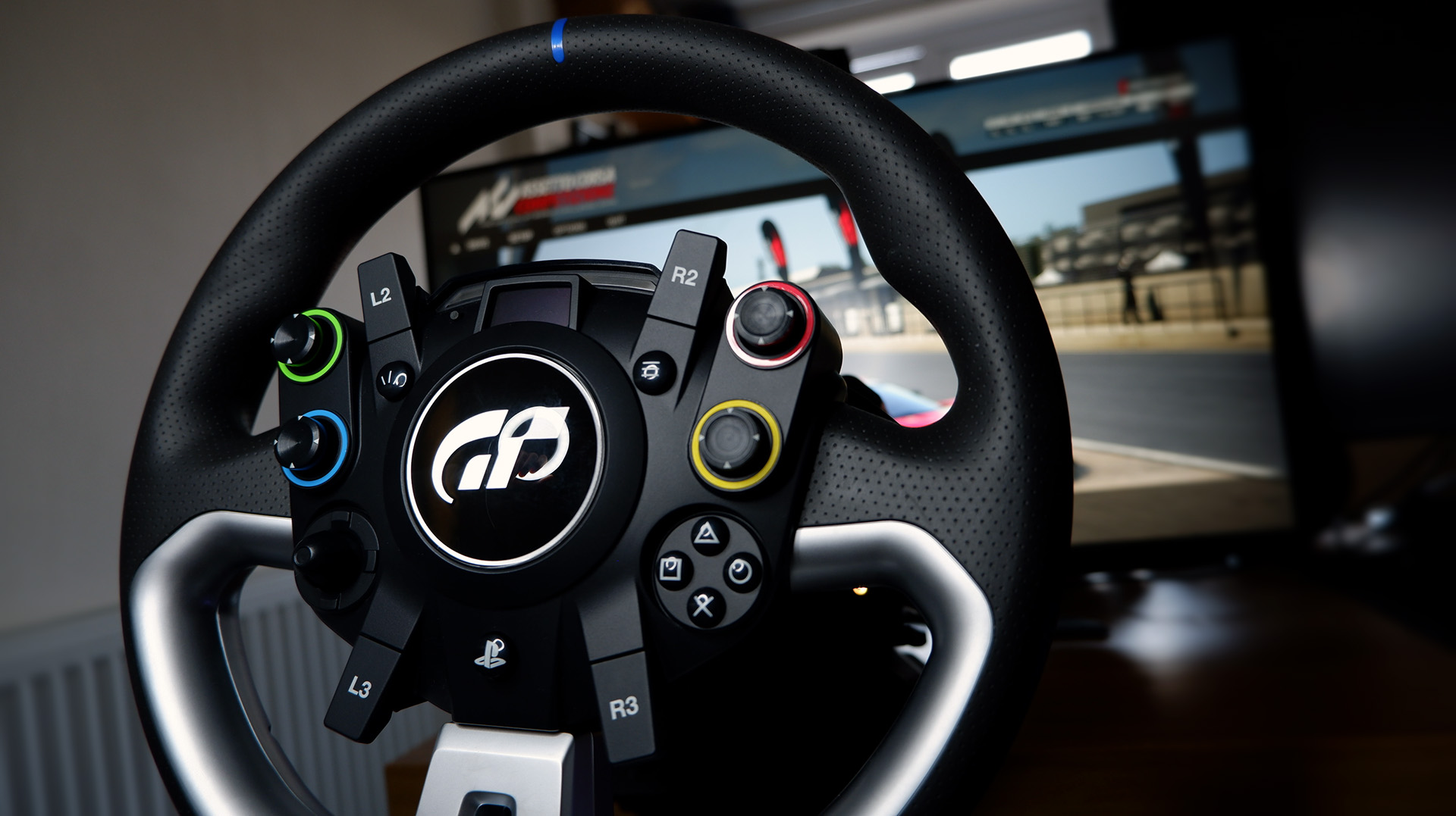The Fanatec GT DD Pro racing wheel and wheelbase on a desk with monitor playing Assetto Corsa behind.