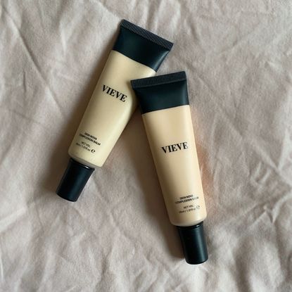 Original image showing two light shades of the VIEVE Skin Nova Complexion Balm set against a dusky pink fabric background