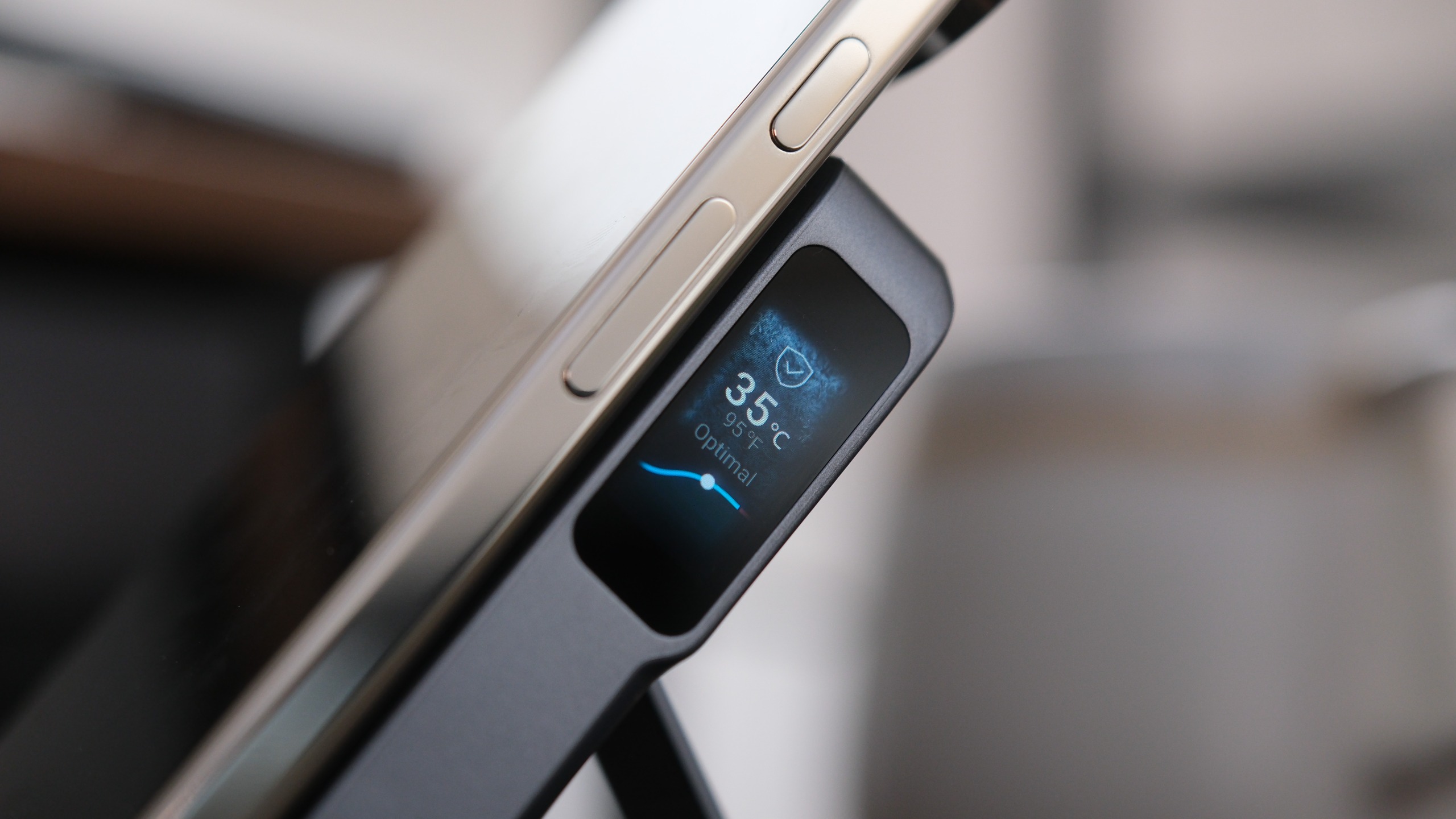 Close-up of the Anker MagGo Power Bank 2 Pro attached to a smartphone, with its smart display showing a temperature reading of 35&amp;deg;C.