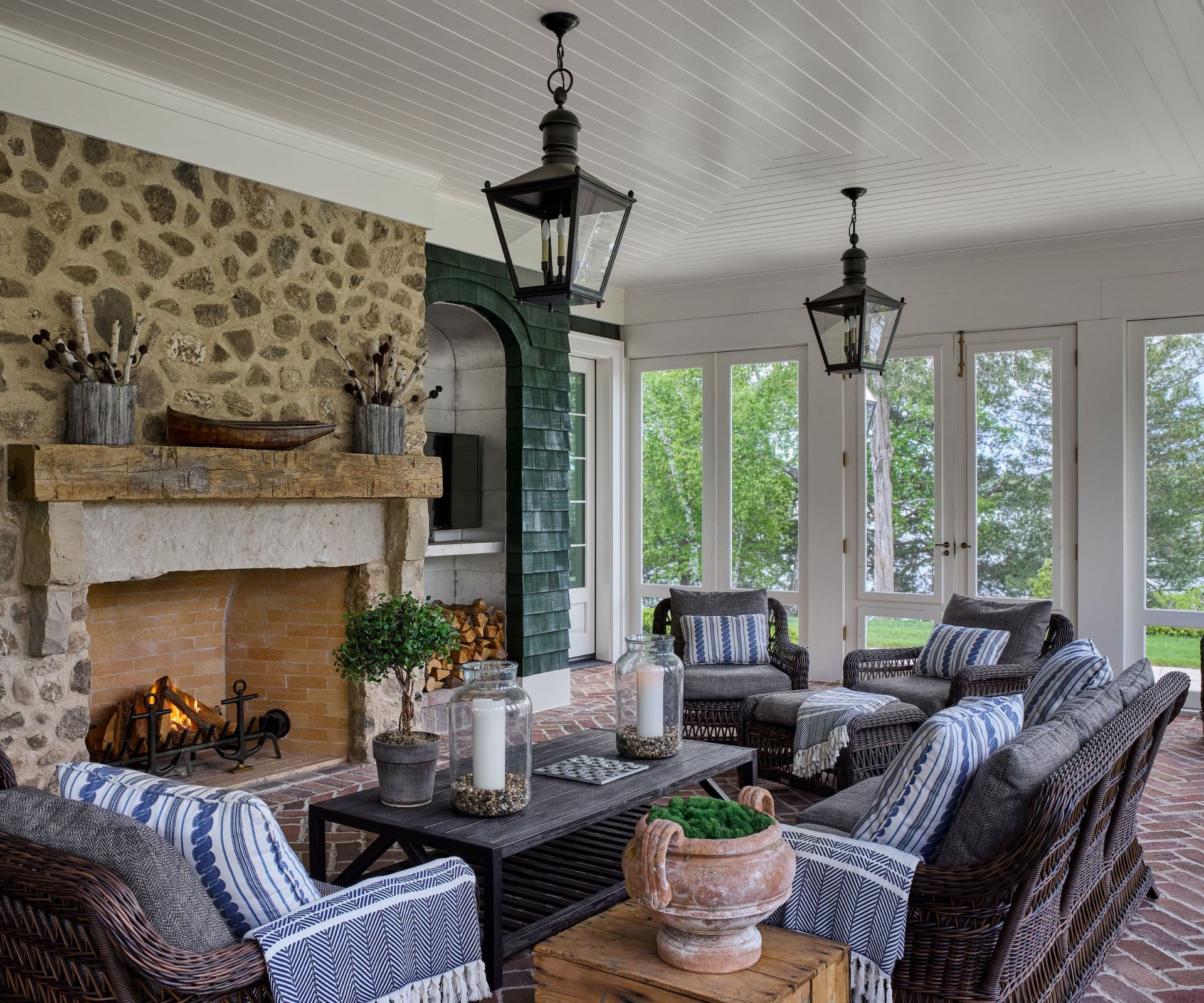 porch seating area with rattan furniture and brick floor and stone fireplace with windows all round