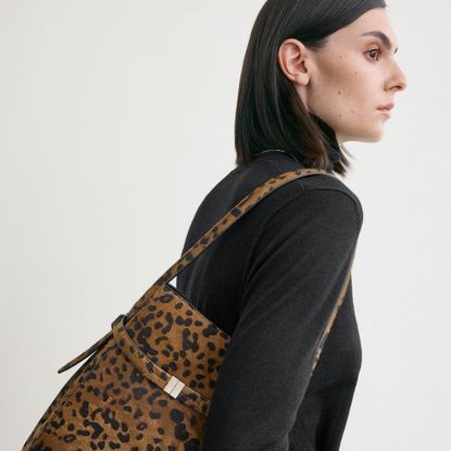 a model wearing a toteme top and leopard print bag