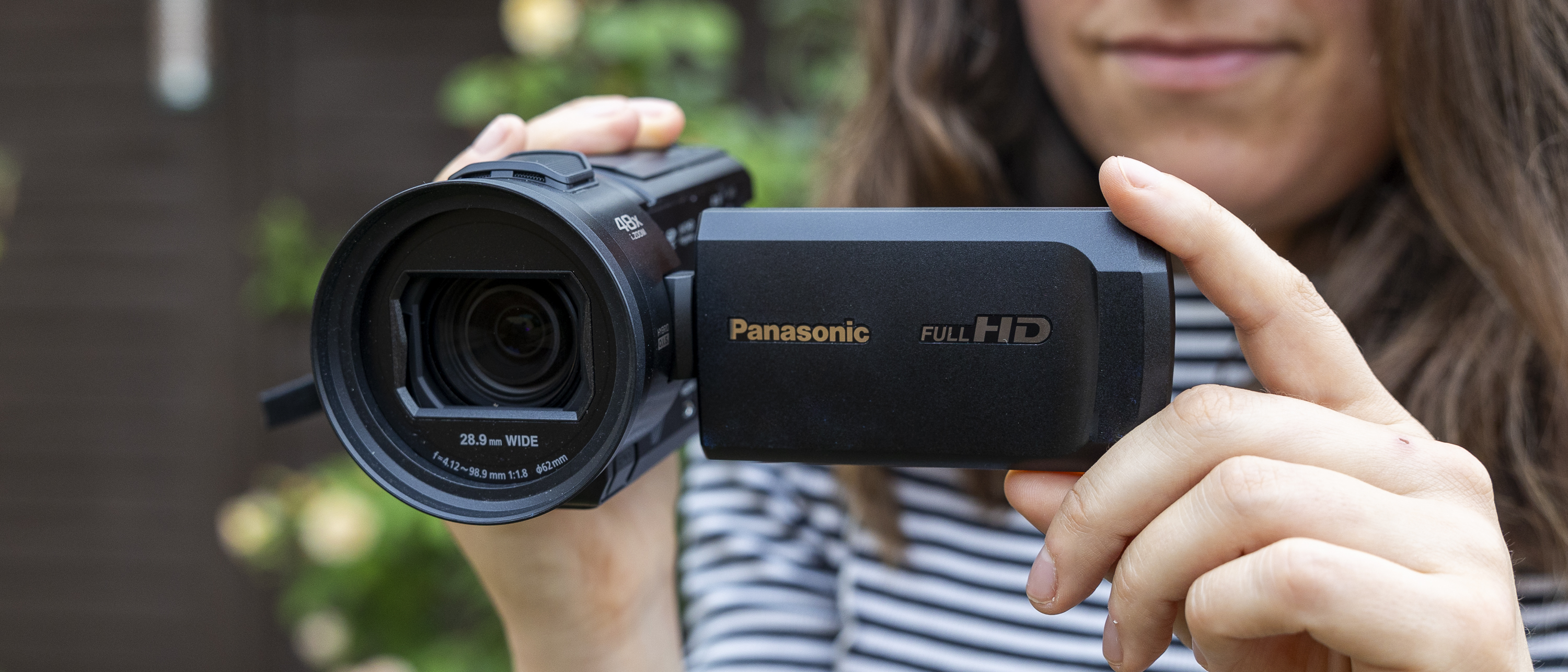 A close up of the Panasonic HC-V900 held by a female in a garden