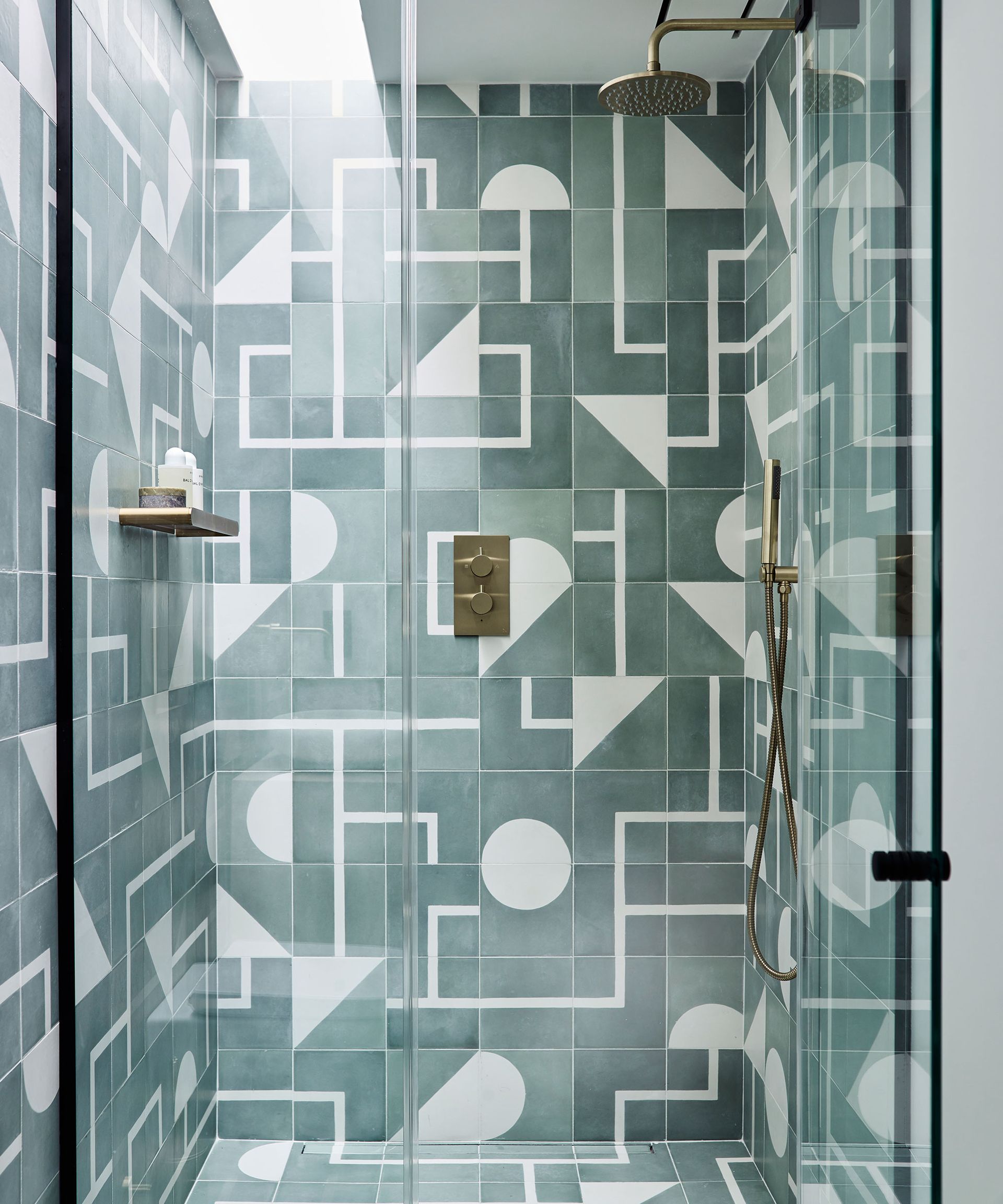 Walk in shower with graphic tiles and brass shower head