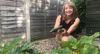 Author holding homegrown zucchini in her own yard