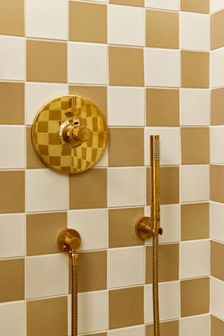 Bright yellow chequered tiled shower with brass fixtures